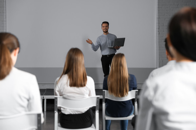 Male business trainer with laptop giving lecture in conference room with projection screen