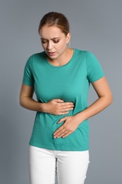 Woman suffering from stomach pain on grey background