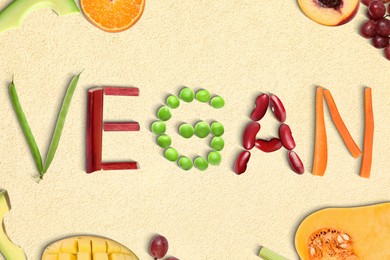 Word VEGAN made of different fresh tasty vegetables on beige background, flat lay
