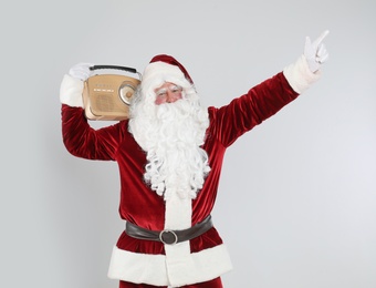 Santa Claus with vintage radio on light grey background. Christmas music