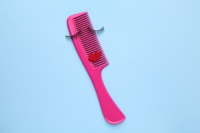 False eyelashes, red lips and hair comb on light blue background, top view