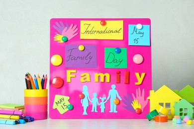 Magnetic board with text International Family Day and paper cutouts on white table