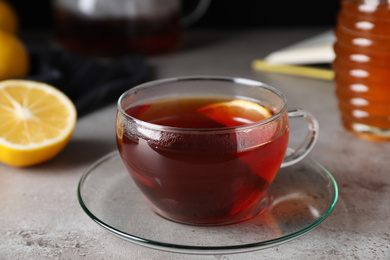 Photo of Fresh tea with honey and lemon on light grey table, closeup