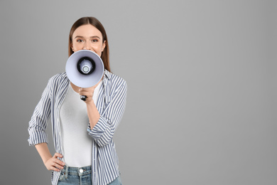 Young woman with megaphone on light grey background. Space for text