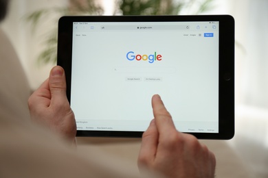 MYKOLAIV, UKRAINE - OCTOBER 27, 2020: Man using Google search engine on tablet against blurred background, closeup
