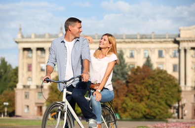 Happy couple riding bicycle outdoors on sunny day