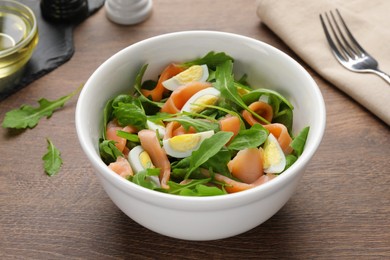 Photo of Delicious salad with boiled eggs, salmon and arugula on wooden table, closeup