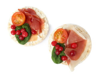 Puffed rice cakes with prosciutto, berries and tomato isolated on white, top view