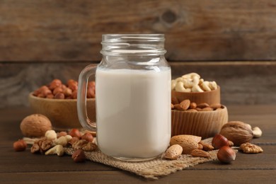 Vegan milk and different nuts on wooden table