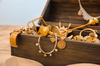 Open wooden treasure chest on sandy beach, closeup