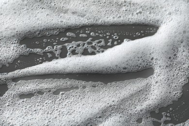 Photo of White washing foam on dark gray background, top view