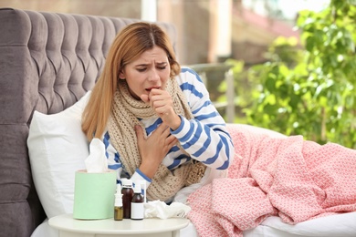 Woman suffering from cough and cold in bed at home