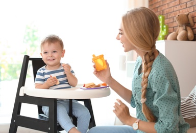 Woman feeding her child in highchair at home. Healthy baby food