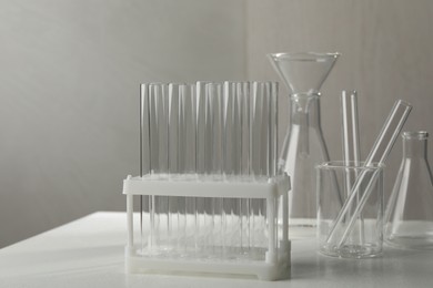 Set of laboratory glassware on white table against grey background