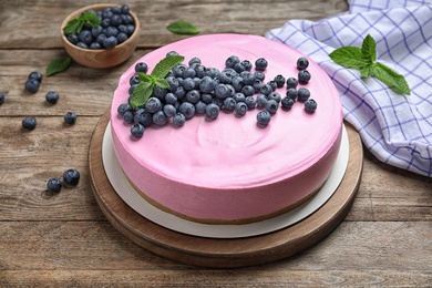 Board with tasty blueberry cake on wooden table