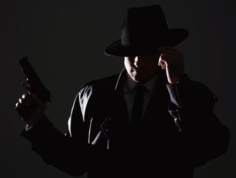 Old fashioned detective with gun on dark background
