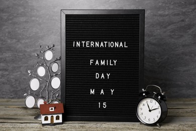 Happy Family Day. Black letter board with text, clock, house model and photo frame on wooden table