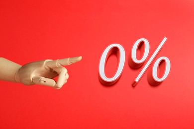 Wooden mannequin hand pointing at sign of zero percent on red background. Special promotion