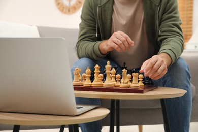 Man playing chess with partner through online video chat in living room, closeup
