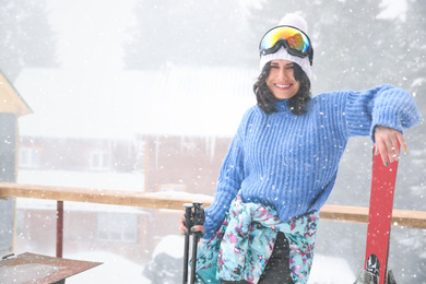 Young woman with skis wearing winter sport clothes and goggles outdoors