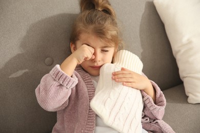 Ill girl with hot water bottle suffering from cold at home