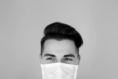 Man wearing medical face mask on light background. Black and white photography