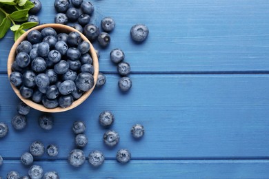 Tasty fresh blueberries on blue wooden table, flat lay. Space for text