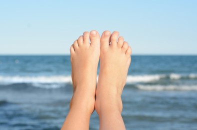 Photo of Child resting near sea, closeup of feet