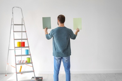 Young man choosing color for wall indoors