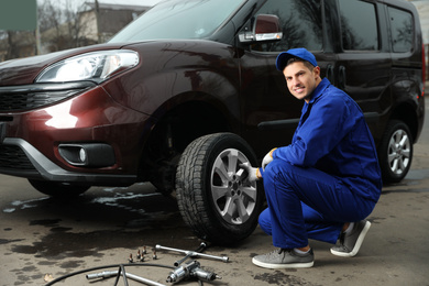 Worker changing car wheel at tire service
