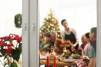 Photo of Happy family enjoying festive dinner at home, view from outside. Christmas celebration