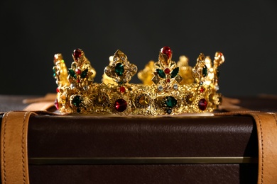 Beautiful golden crown on suitcase against black background. Fantasy item