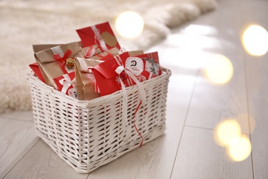 Photo of Basket full of gifts in paper bags for Christmas advent calendar on floor, space for text