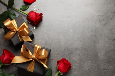Two black gift boxes and beautiful roses on dark background, flat lay. Space for text