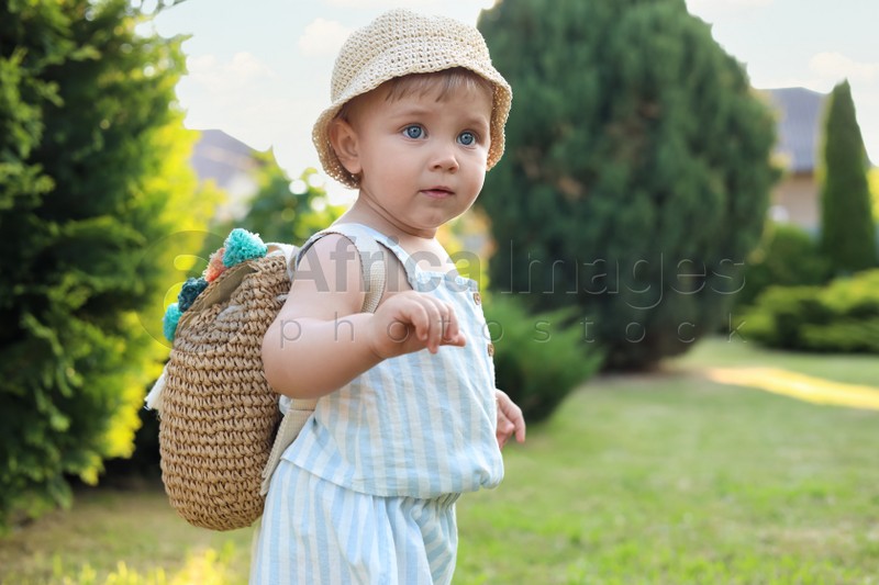 Cute little girl in stylish clothes with knitted backpack outdoors on sunny day. Space for text