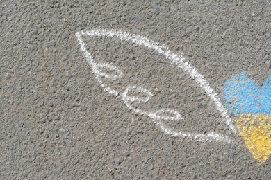 Photo of Heart and wings drawn with blue and yellow chalks on asphalt outdoors, closeup. Space for text