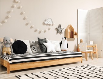Photo of Cute kids room with stylish comfortable floor bed and toys. Montessori interior