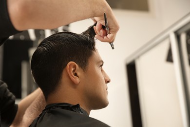 Professional barber making stylish haircut in salon, closeup. Space for text