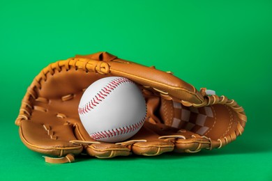 Photo of Catcher's mitt and baseball ball on green background. Sports game