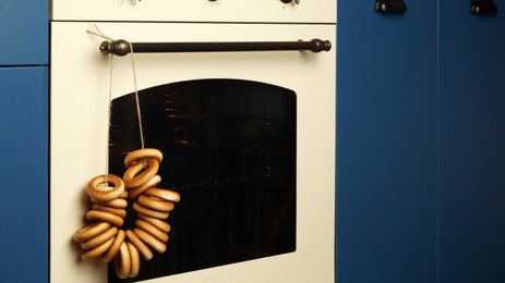 Photo of Bunch of delicious ring shaped Sushki (dry bagels) hanging near oven in kitchen
