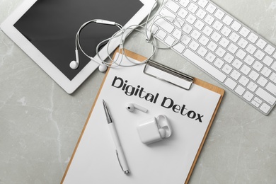 Photo of Flat lay composition of clipboard with words DIGITAL DETOX on light grey marble background