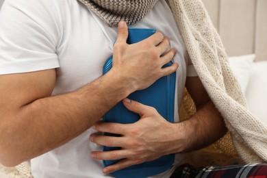 Ill man holding hot water bottle on his chest, closeup