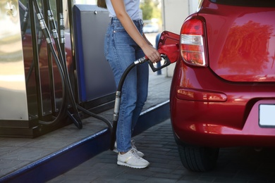 Photo of Young woman refueling car at self service gas station, closeup