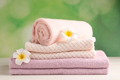 Soft folded towels and plumeria flowers on white wooden table
