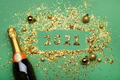 Flat lay composition with confetti, festive decor and bottle of champagne on green background. New Year celebration