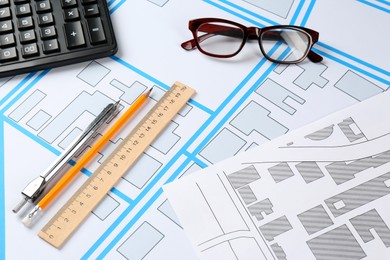 Office stationery and eyeglasses on cadastral maps of territory with buildings