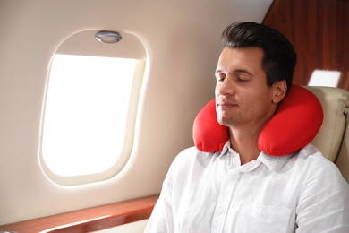 Handsome man with neck pillow sleeping during flight. Ait travel