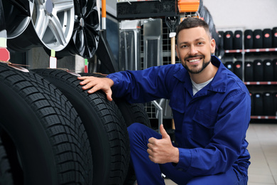 Photo of Male mechanic with car tires in auto store