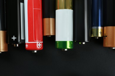 Many different batteries on black background, flat lay