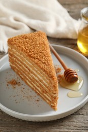 Slice of delicious layered honey cake served on wooden table, closeup